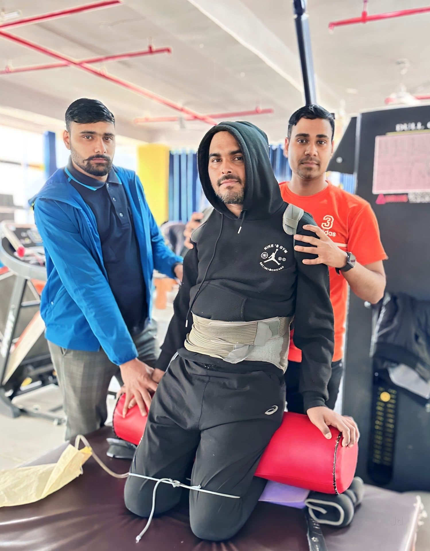 Two Quick Walk physiotherapists supporting a patient in a trunk harness during a seated balance exercise